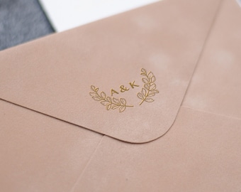 May include: A light brown envelope with a gold wax seal featuring the initials "A&K" surrounded by a wreath design.