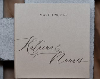 Puede incluir: Un álbum de fotos de lino beige con el texto "MARCH 28, 2025" y los nombres "Katrina & Norris" escritos en cursiva.