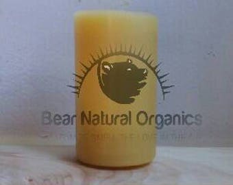 Op de afbeelding: Een gele bijenwaskaars met een berenlogo en de tekst "Bear Natural Organics" gedrukt op de zijkant.