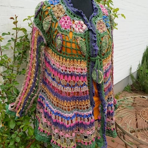 May include: A colorful crocheted cardigan with a floral design and a tie closure. The cardigan is made with a variety of colors, including green, pink, purple, blue, and yellow.