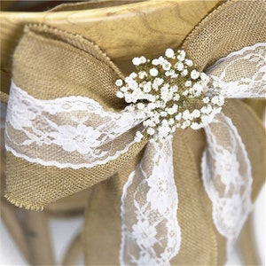 May include: A burlap chair sash with white lace trim and a small bouquet of white baby's breath.