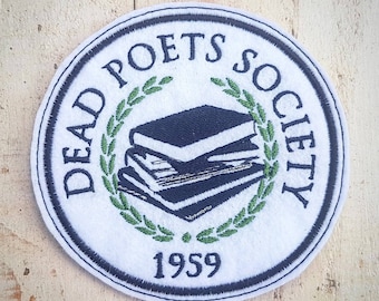 Può includere: Toppa circolare con la scritta "DEAD POETS SOCIETY" in blu navy, che circonda una pila di libri e una corona d'alloro. L'anno "1959" è in basso. La toppa ha uno sfondo bianco e un bordo blu navy.