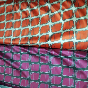 K&ouml;nnte beinhalten: Zwei Stoffst&uuml;cke mit einem sich wiederholenden Muster aus stilisierten Elefanten. Der obere Stoff ist orange auf cremefarbenem Hintergrund. Der untere Stoff ist rosa auf dunkelgrauem Hintergrund.