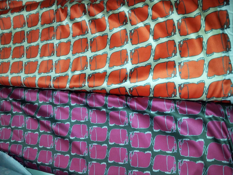 K&ouml;nnte beinhalten: Zwei Stoffst&uuml;cke mit einem sich wiederholenden Muster aus stilisierten Elefanten. Der obere Stoff ist orange auf cremefarbenem Hintergrund. Der untere Stoff ist rosa auf dunkelgrauem Hintergrund.