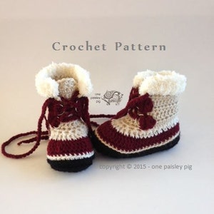 May include: A pair of crocheted baby booties with a burgundy, cream, and white color scheme. The booties have a lace-up design and a fluffy white trim. The text "Crochet Pattern" is at the top of the image and "copyright © 2015 - one paisley pig" is at the bottom.