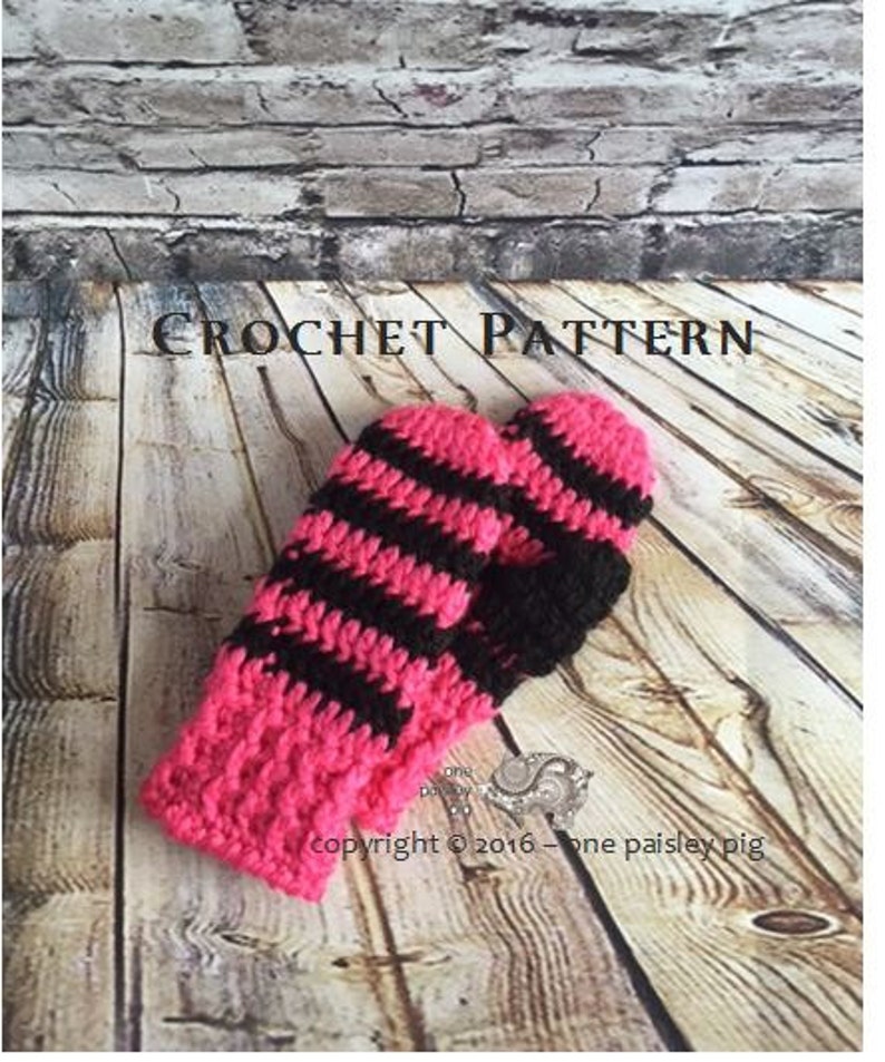 May include: A pair of crochet mittens featuring horizontal stripes in alternating hot pink and black yarn. The text CROCHET PATTERN is visible at the top, and the text copyright 2016 one paisley pig is visible near the bottom of the mittens.