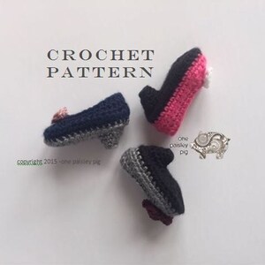 May include: Three miniature crochet shoes with heels, featuring navy blue, black, and pink yarn colors. The text CROCHET PATTERN is visible at the top, with one paisley pig and copyright 2015 - one paisley pig text printed near the shoes.