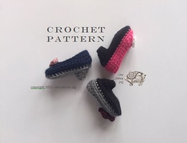 May include: Three miniature crochet shoes with heels, featuring navy blue, black, and pink yarn colors. The text CROCHET PATTERN is visible at the top, with one paisley pig and copyright 2015 - one paisley pig text printed near the shoes.