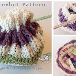 May include: A crocheted drawstring bag with a green, white, and purple striped pattern. The bag is open and shows the inside, which is lined with a white fabric. The bag is made with a crochet stitch that creates a textured look. The bag is perfect for storing small items like makeup or jewelry.