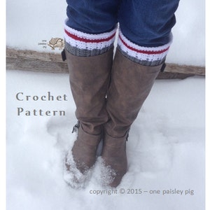 Puede incluir: Polainas de crochet para botas en gris, blanco y rojo con un patrón de punto de crochet blanco. Las polainas se llevan sobre botas marrones y la persona está de pie en la nieve. La imagen incluye el texto "Crochet Pattern" y "copyright © 2015 - one paisley pig".