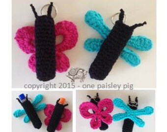 May include: A selection of crocheted butterfly keyrings in pink, black, and teal. Each butterfly has a black body and wings, with a silver keyring. The image includes the text "copyright 2015 - one paisley pig."