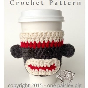 May include: Crochet coffee cosy pattern featuring a monkey face with red, white and grey yarn. The cosy is on a white takeaway cup. The text "Crochet Pattern" is at the top of the image. The text "copyright 2015 - one paisley pig" is at the bottom of the image.
