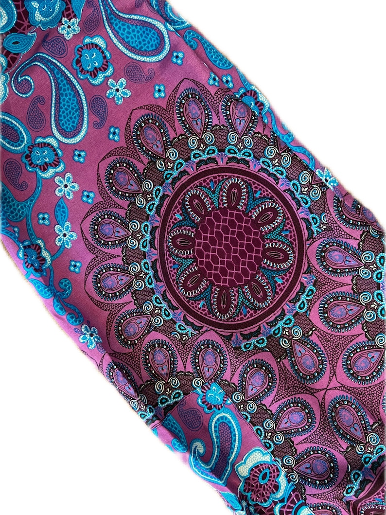 May include: Purple fabric with a blue and white paisley pattern. The fabric features a large, intricate mandala design in the center.