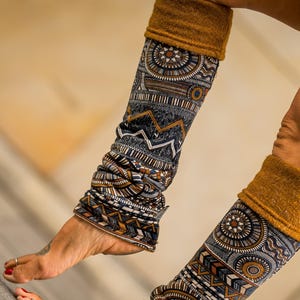 Peut inclure: Jambières avec un motif géométrique dans les tons de bleu, marron et blanc. Les poignets sont jaune moutarde uni. Les jambières sont regroupées autour des chevilles.