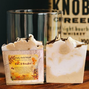 May include: Two bars of artisan soap, labeled "Rum & Bourbon" with a light brown and white swirl design. The soap is next to a clear glass and a label with the brand name and ingredients. The soap weighs 4.5 oz.