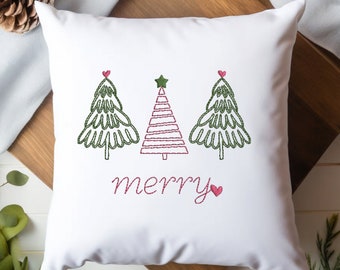 Può includere: Cuscino bianco con alberi di Natale ricamati in verde e la parola "buon" in filo rosa. Gli alberi hanno strisce rosse e una stella in cima.
