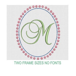 May include: An embroidery design featuring a light green cursive letter M centered within an oval frame. The frame consists of a thin blue line surrounded by a border of small pink circular dots. The text TWO FRAME SIZES NO FONTS appears below.
