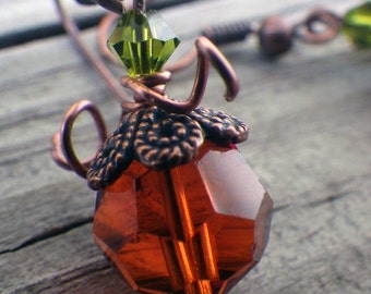 May include: Copper and brown teardrop shaped glass earrings with a green crystal accent.