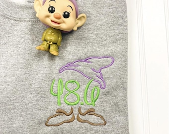 May include: A gray sweatshirt with a purple, green, and brown embroidered design of a gnome. The gnome is wearing a purple hat and has a green beard. The letters "48.C" are embroidered in green on the gnome's hat.