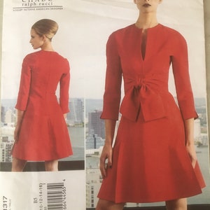 Pode incluir: Um padrão de vestido vermelho de Chado Ralph Rucci para Vogue Patterns. O padrão apresenta um vestido até ao joelho com um detalhe de laço na cintura e mangas três quartos. O número do padrão é V1317, e o intervalo de tamanhos é B5 (8-10-12-14-16).