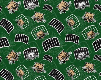 May include: A dark green fabric featuring a repeating pattern of the Ohio University bobcat mascot head in tan and white, alongside the word OHIO in bold black letters with white outlines, arranged in a dense, multi-directional layout.