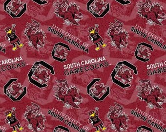 May include: A maroon fabric pattern featuring the University of South Carolina Gamecocks logo, the mascot Cocky, and the text University of South Carolina and South Carolina Gamecocks printed in white and black throughout the repeating design.