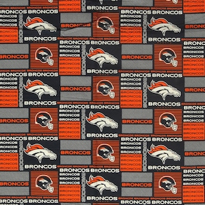 May include: A fabric pattern featuring the Denver Broncos logo, a stylized horse head, and football helmets in orange, white, and navy blue. The design includes repeating text that reads BRONCOS in white and orange against a dark background.