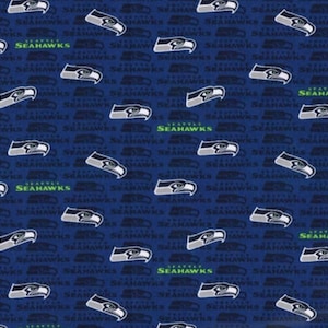 May include: A dark blue fabric featuring a repeating pattern of the Seattle Seahawks logo in white, grey, and blue, interspersed with the text Seattle Seahawks printed in a bright lime green font across the surface of the material.