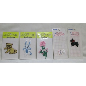 Puede incluir: Una colección de apliques Sew Perfect y Wrights. Los apliques incluyen un gato amarillo, un conejo azul y blanco, una rosa rosa, dos flores blancas y un perro negro con un lazo rojo.