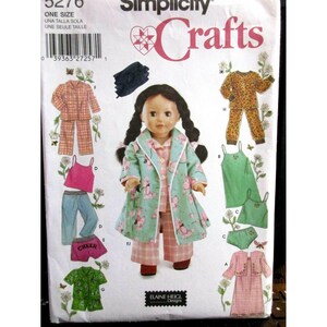 Puede incluir: Patrón de costura Simplicity Crafts para ropa de muñecas. El patrón incluye varios conjuntos, como pijamas, una camiseta sin mangas con vaqueros, pantalones cortos con la palabra "CHEER" y un vestido con chaqueta. La muñeca de la imagen lleva una bata y pijama.