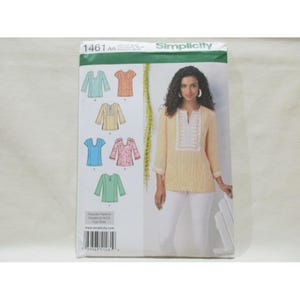 Op de afbeelding: Een Simplicity 1461 AA naaipatroon-envelop met een geel-wit gestreepte tuniek met een witte sluiting en driekwartmouwen. De omslag toont zes variaties van de tuniek in verschillende kleuren en patronen, waaronder effen blauw, bloemenprints en oranje ontwerpen.