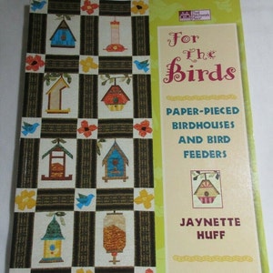 Puede incluir: Un libro titulado "For the Birds" con un diseño de colcha de retazos en la portada. La colcha presenta casas para pájaros y comederos hechos con piezas de papel en varios colores y diseños. El libro es de Jaynette Huff y trata sobre casas para pájaros y comederos hechos con piezas de papel.