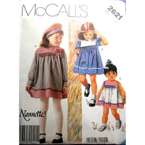 Puede incluir: Patrón de costura McCall's para vestidos de niña. El patrón presenta ilustraciones de tres diseños de vestidos diferentes. La portada incluye el texto "McCall's" y "Nannette", junto con un código de barras y un número de patrón.