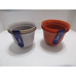 May include: Two sets of three plastic flower pots. One set is light gray, the other is orange. Each pot has a rounded shape and a dark blue label with the number "3" and the words "PACK PAQUET DE".
