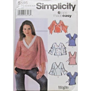 May include: Simplicity sewing pattern for six tops. The pattern features a woman wearing a red patterned top with a white trim. The pattern includes various top designs, including V-neck and sleeve variations. The text "6 tops made easy" is visible.