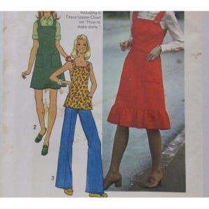 May include: Vintage sewing pattern featuring three different outfits. The outfits include a green jumper dress, a floral top with blue bell-bottom pants, and a red dress with a ruffled hem. The text on the pattern reads, "Including a Tissue lesson Chart on 'How to make darts.'"