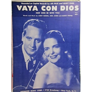 May include: Sheet music cover for "Vaya Con Dios" by Les Paul and Mary Ford. The cover features a blue background with a portrait of a man and woman. The title and artist names are in white text.