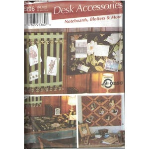 May include: A product image showcasing various desk accessories. The image features note boards, blotters, and more. The accessories are decorated with floral patterns, stripes, and photos. The text "Desk Accessories" and "Noteboards, Blotters & More" are visible.