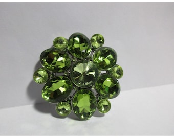 Broche de cristal facetado verde sobre base plateada de 5 cm de diámetro