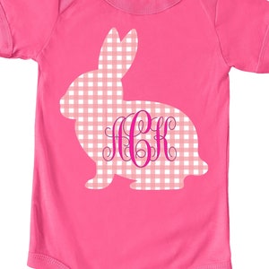 May include: Pink baby onesie with a pink and white gingham bunny silhouette and the monogram "JCK" in pink.