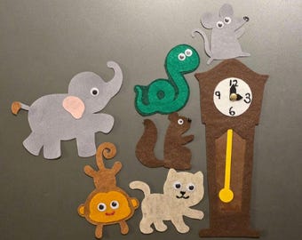 May include: A set of felt cutouts featuring a gray elephant, a green snake, a brown squirrel, a tan monkey, a light tan cat, a gray mouse, and a brown grandfather clock with a white face, black numbers, and a yellow pendulum.