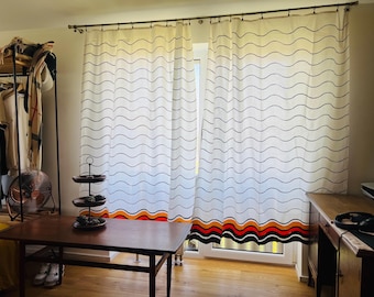 May include: A pair of white curtains featuring thin black horizontal wavy lines across the fabric. The bottom hem of the curtains displays a bold, multi-colored pattern consisting of thick, wavy bands in orange, red, and black colors.