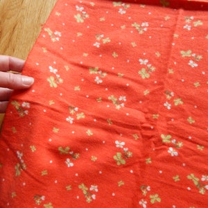 Puede incluir: Tela roja con un patr&oacute;n floral blanco y verde.