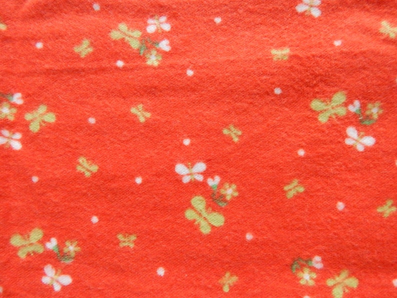 Puede incluir: Tela roja con un patr&oacute;n floral blanco y amarillo. La tela tiene una superficie texturizada.