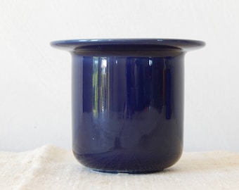 May include: A dark blue ceramic vase with a wide, rounded rim. The vase has a smooth, glossy finish.