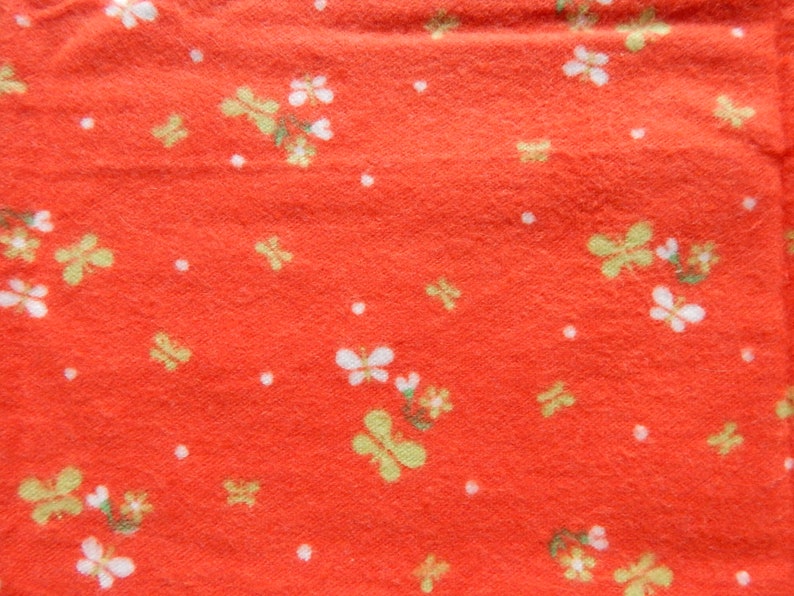 Puede incluir: Tela roja con un patr&oacute;n floral blanco y amarillo. La tela tiene una superficie texturizada.