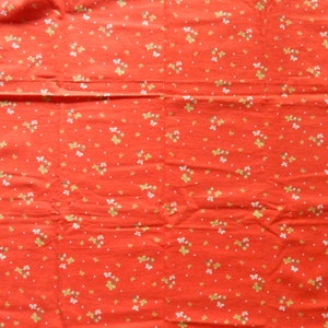 Puede incluir: Tela roja con un patr&oacute;n floral blanco y dorado.