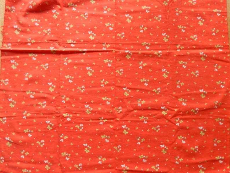 Puede incluir: Tela roja con un patr&oacute;n floral blanco y dorado.