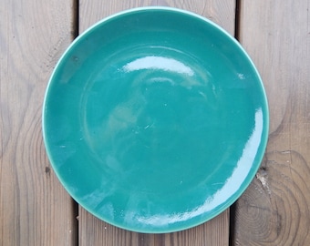 May include: A plain, teal-colored ceramic dinner plate.