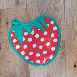 Peut inclure: Manique en forme de fraise avec des pois rouges et blancs et des feuilles vertes.
